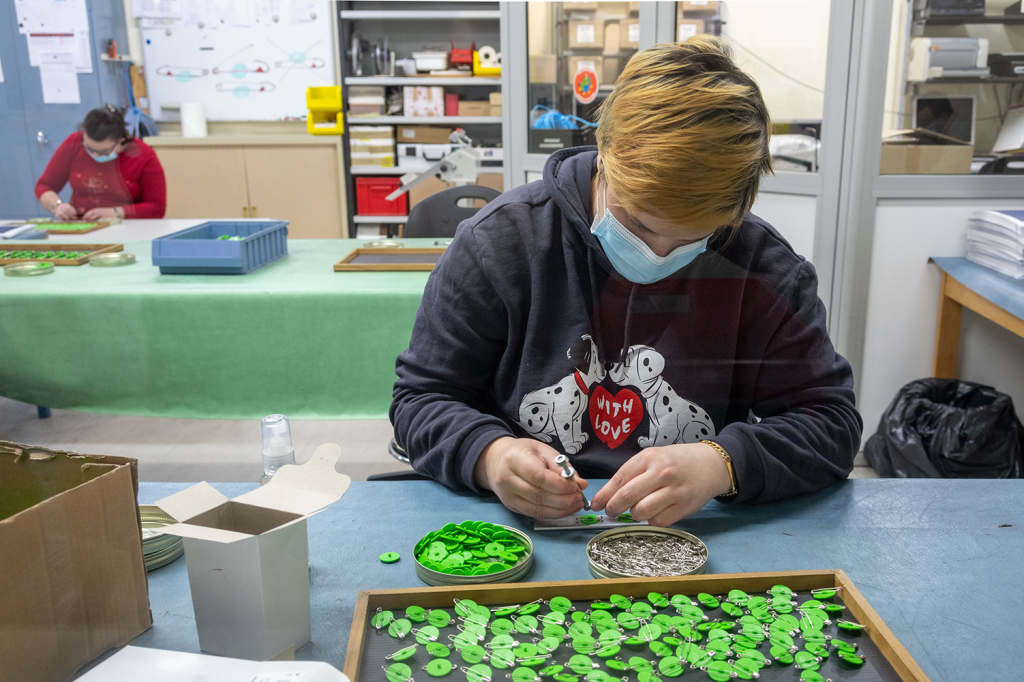 Une employée de l'ESAT assemble le dos de la fleur.